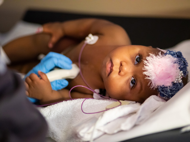 Gabbi Smith, UMMC’s youngest heart transplant patient, holds her sonographer’s hand.